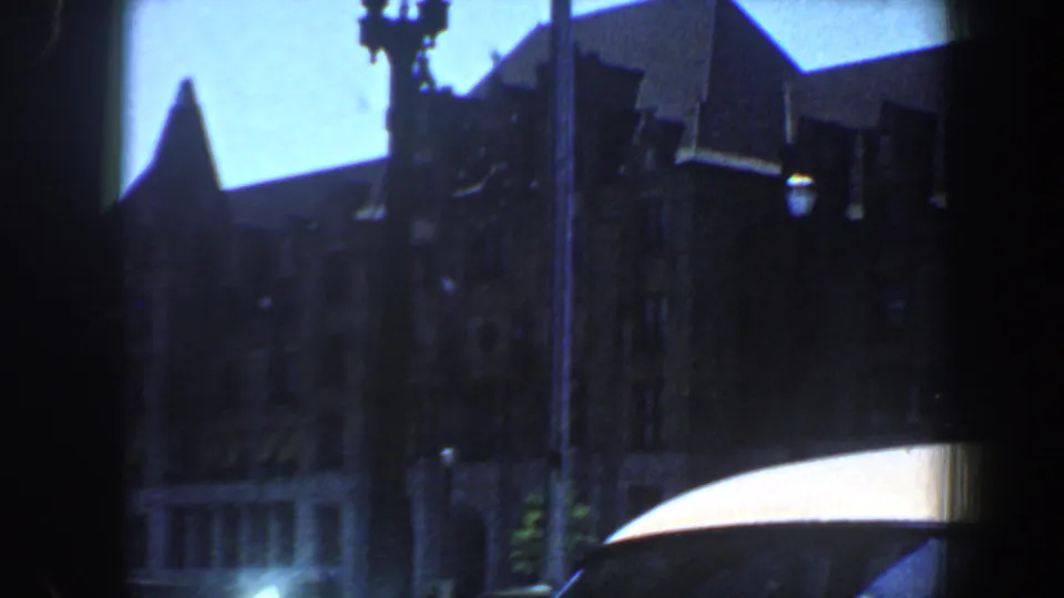 End frame of the 1964 Saint Louis downtown view, with dark building fronts, a street lamp, blue sky, and a bright awning edge.