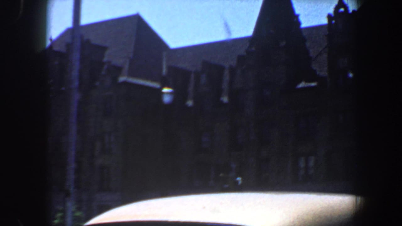 Shadowed gabled building seen above a bright car roof.