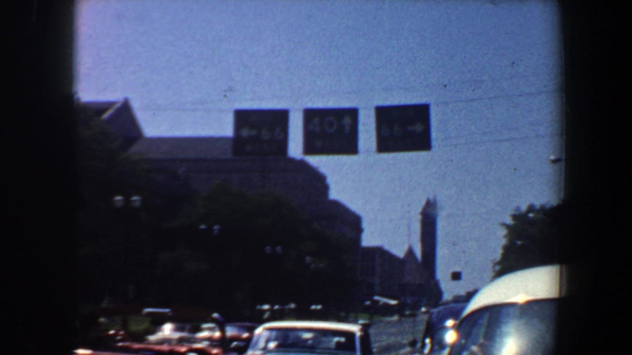 City street with overhead Route 66 and 40 signs above cars.