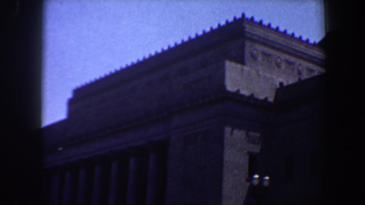 Large columned building seen from the street through a dark film edge.