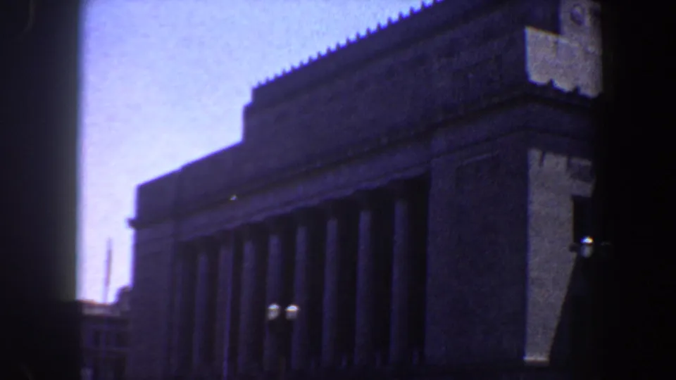 Large Saint Louis building facade with columns, patterned upper wall, street lamps, and soft 8mm exposure shift.