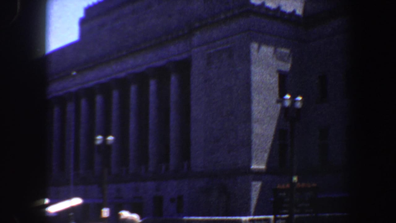 Library corner and colonnade viewed past a dark vertical frame.