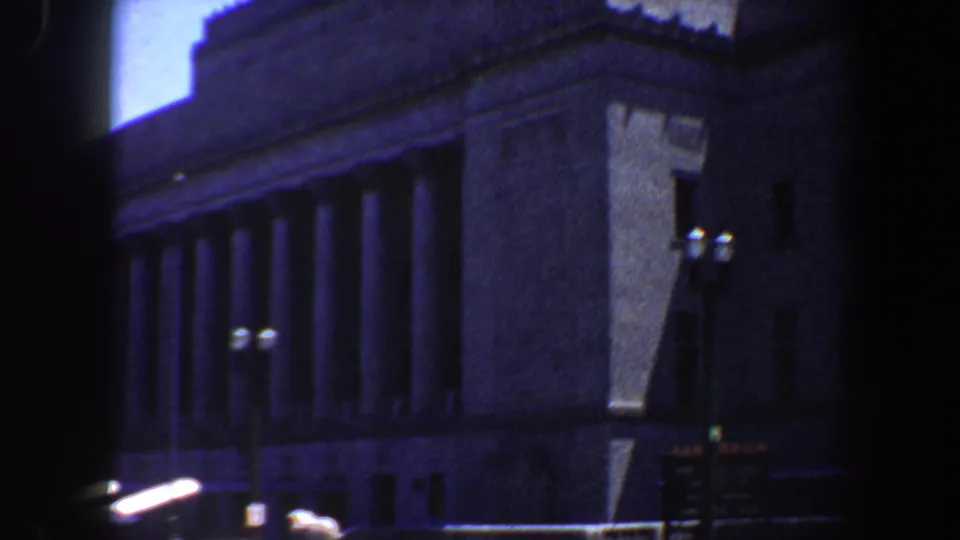 St. Louis City Library exterior in 1964, showing the corner, columns, streetlamps, and a small street sign beyond a dark foreground bar.