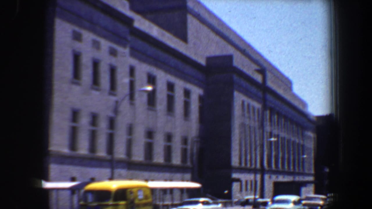 City street with classic cars and a large masonry building.
