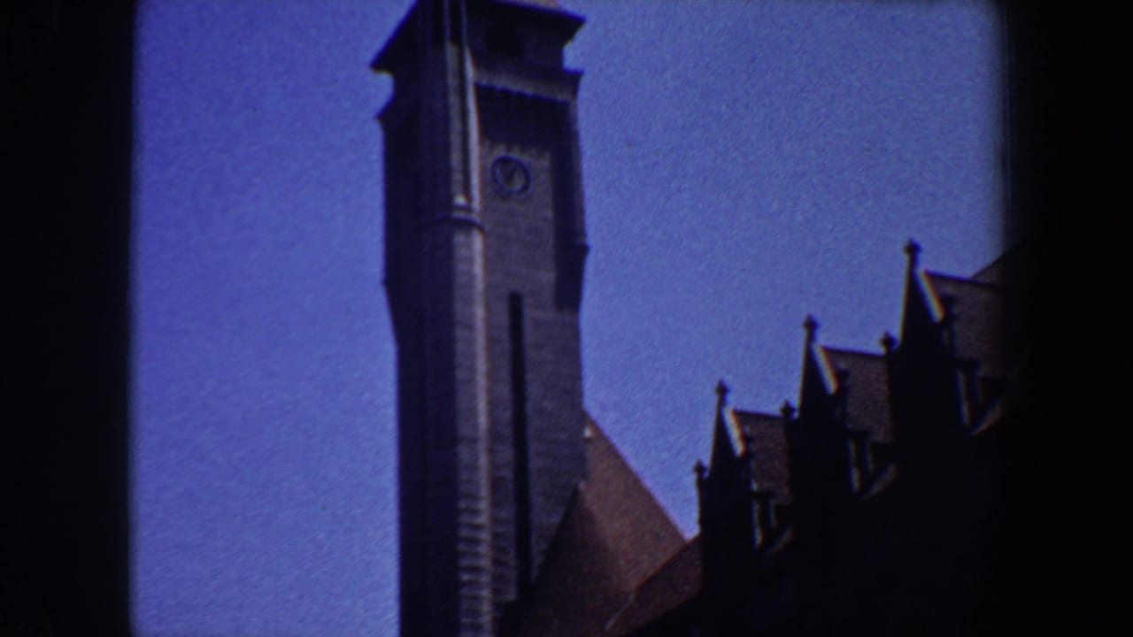 Tall grey tower and adjacent dark roof peaks framed against a deep blue sky.