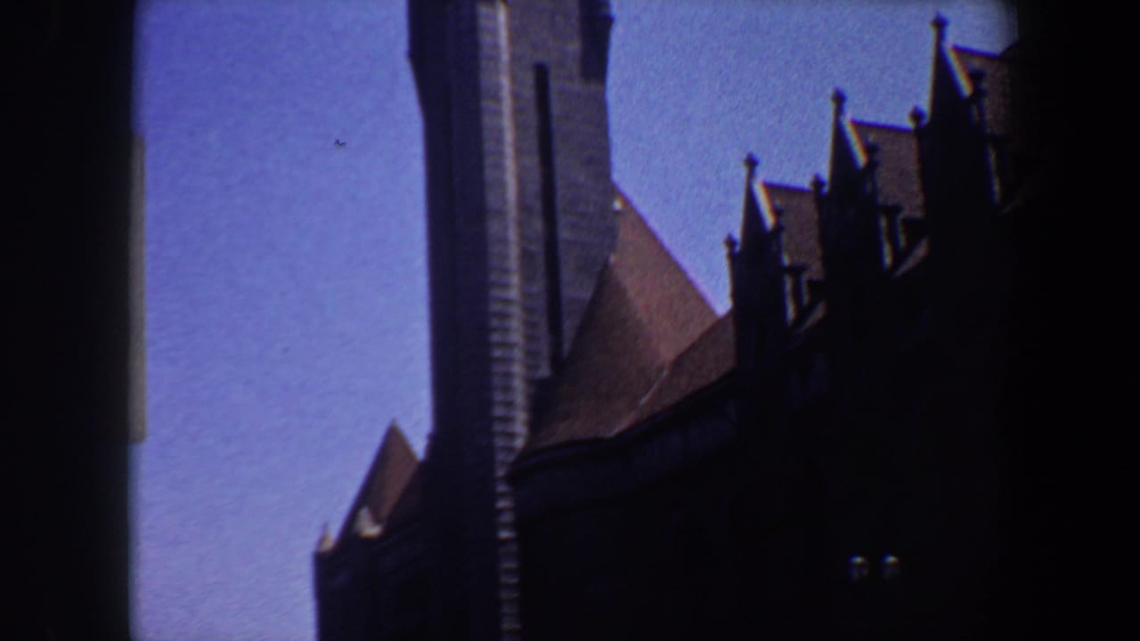 Dark Gothic-style church tower and steep roof silhouetted against a blue sky.