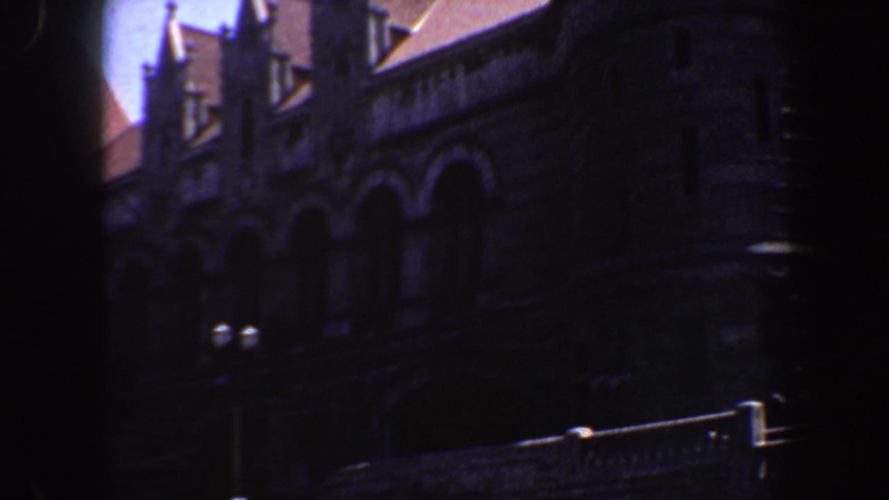 Dark stone Gothic Revival facade with arched openings and roofline shadow.