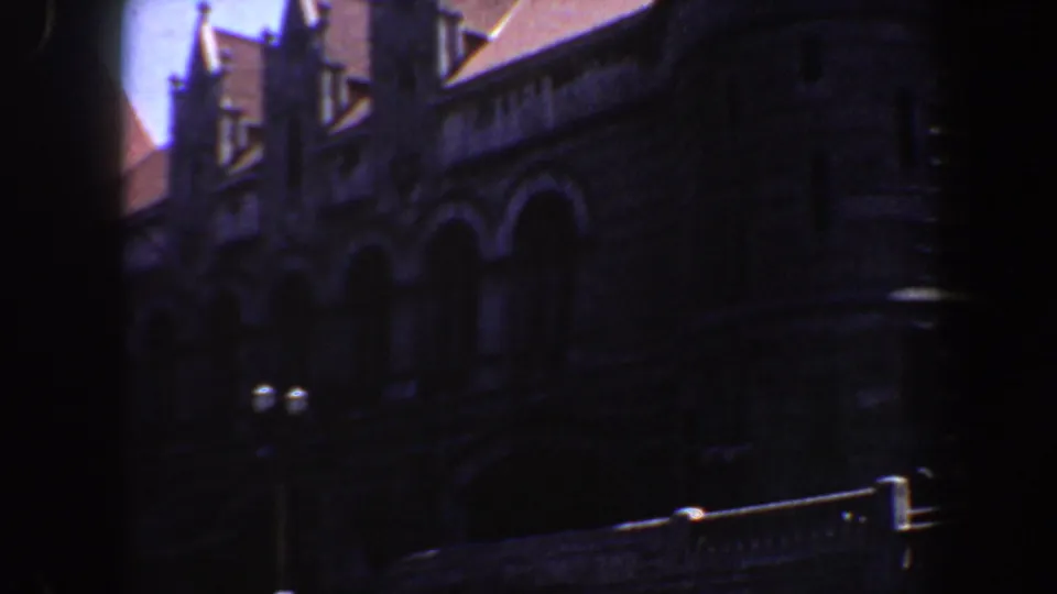 1964 Saint Louis 8mm frame showing a dark stone facade with pointed arches, roof details, and heavy edge shadow.
