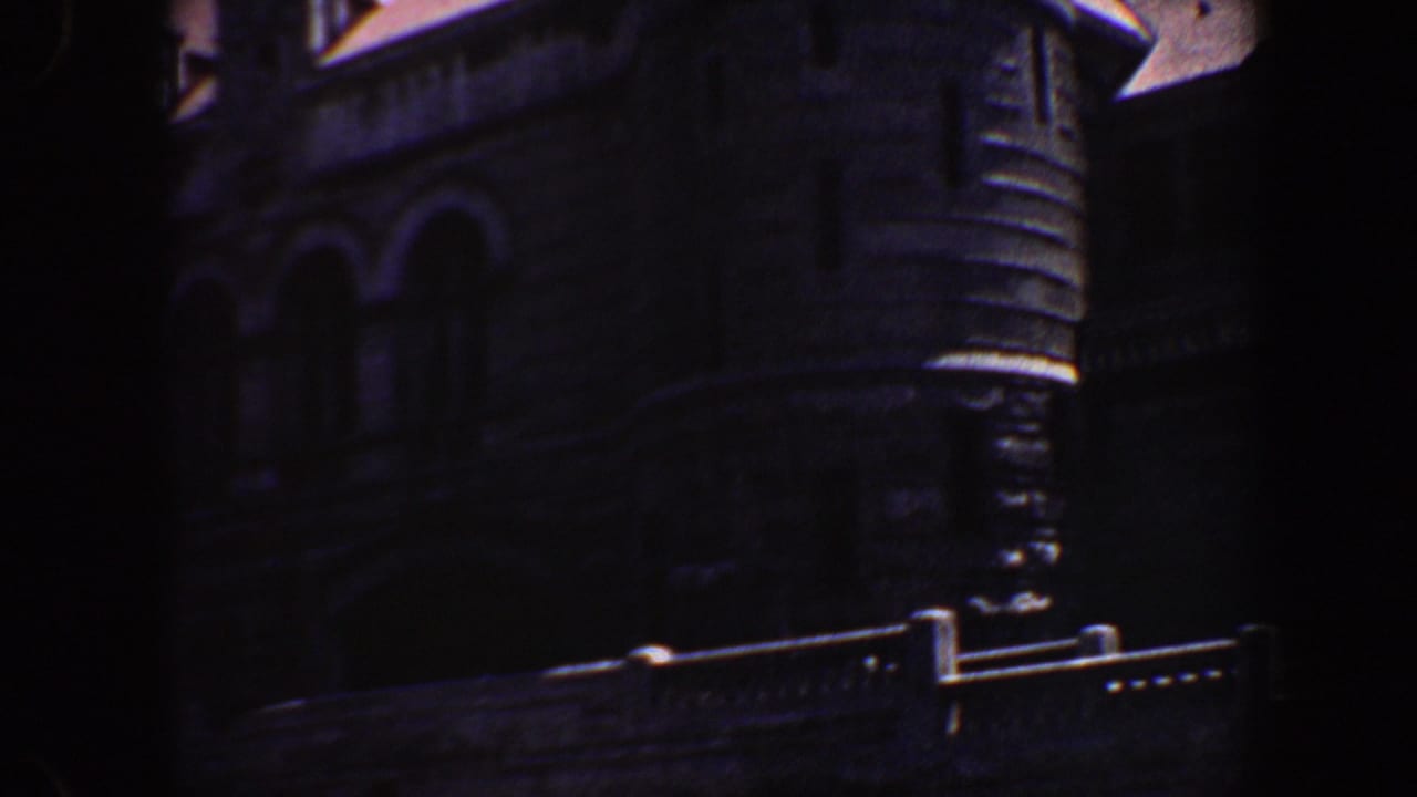 Shadowed building corner with stonework, arched openings, and roof details.