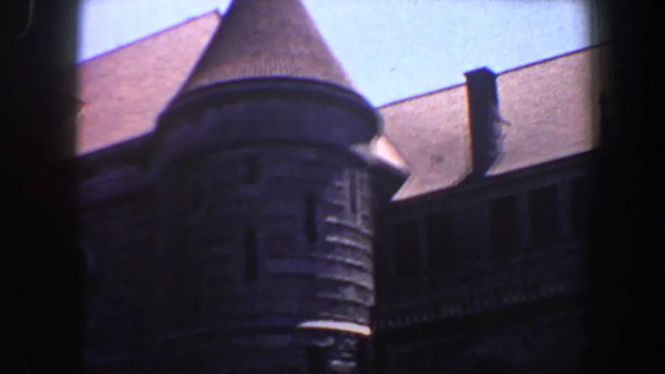 Soft, grainy 8mm footage shows the Saint Louis building's conical turret, small window, and adjoining dark roofline.