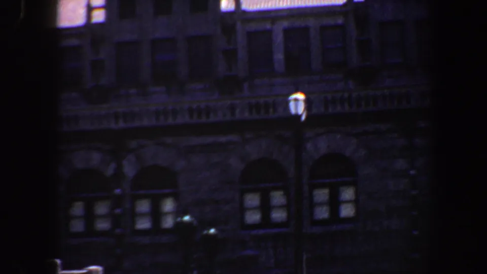 1964 Saint Louis exterior frame with arched lower windows, ornate stone detailing, and a streetlamp in front of the building.