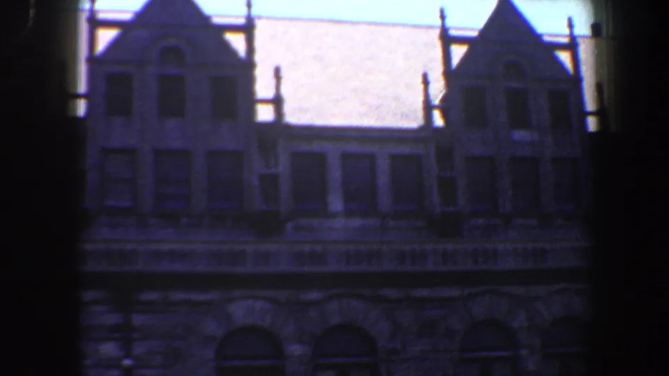 1964 Saint Louis frame showing a historic stone building facade with gables, windows, and dark edge framing.