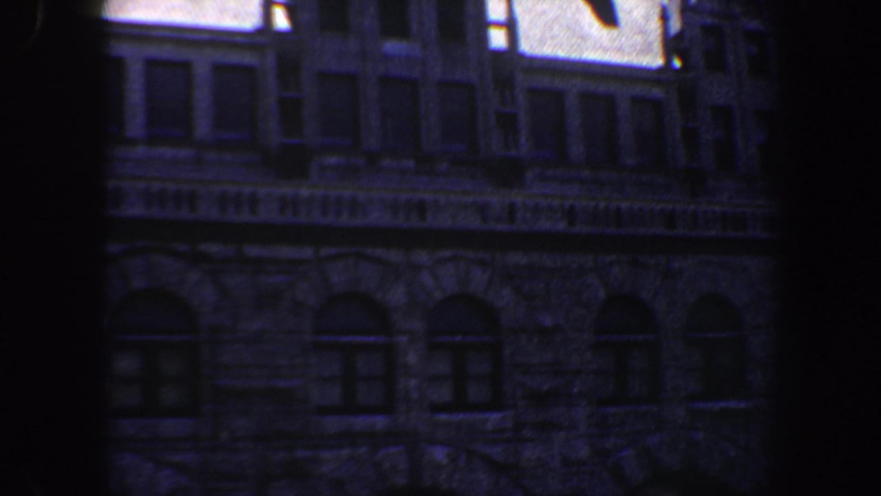 1964 Saint Louis 8mm frame showing a dim stone building facade with arched lower windows and shadowed vertical framing.