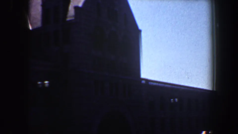 1964 Saint Louis home-movie frame showing the building corner in silhouette with street-level details below.