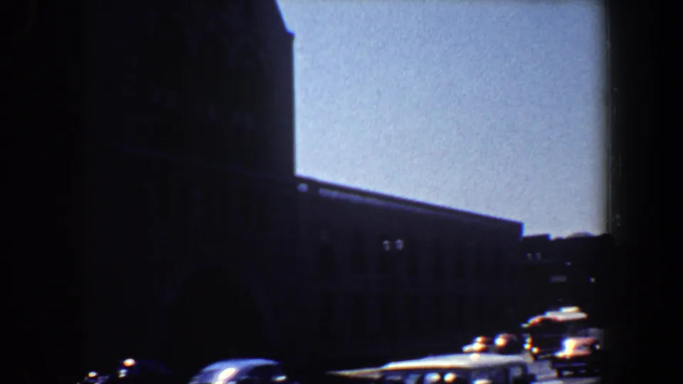 1964 Saint Louis 8mm frame with the stone building in shadow and cars moving along the street below.