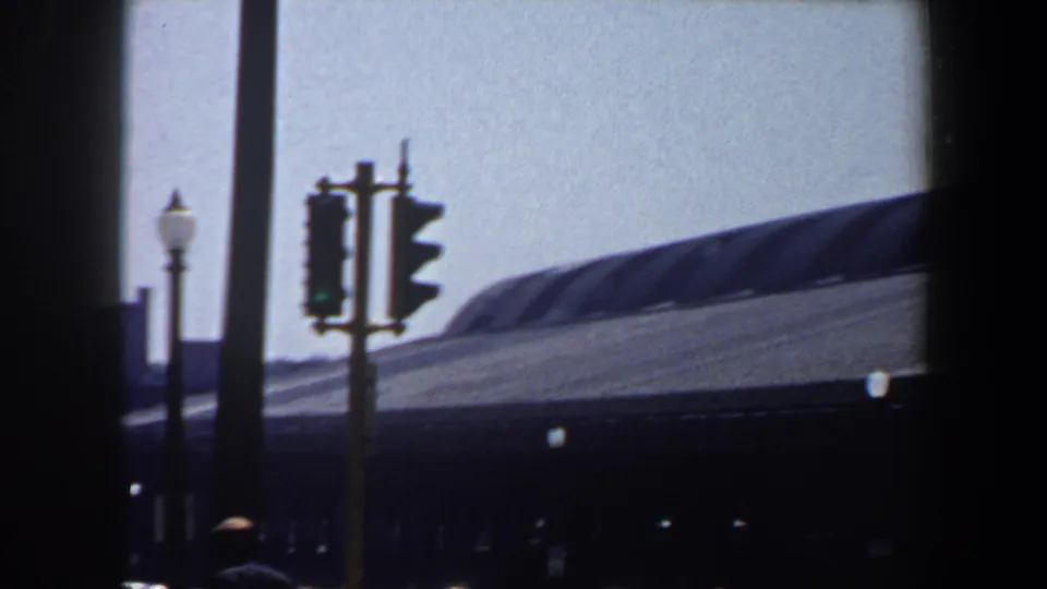 Saint Louis street frame showing traffic signals, street lamps, poles, and a large arched roof structure under daylight.