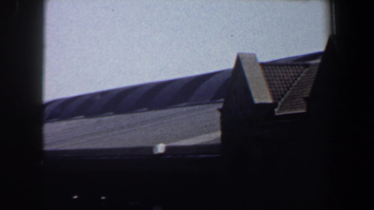 Curved grey roof with a tiled gable peak partly framed by dark vertical edges.