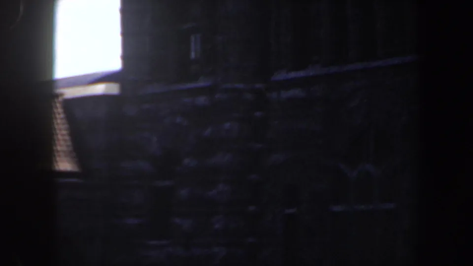 1964 Saint Louis 8mm frame showing a dim stone facade with masonry texture and a bright upper-left window area.