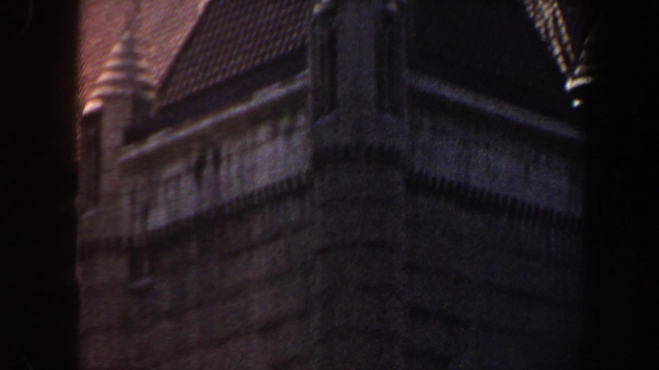 Dark stone building with arched windows and a roofline, partially obscured by frame shadow.