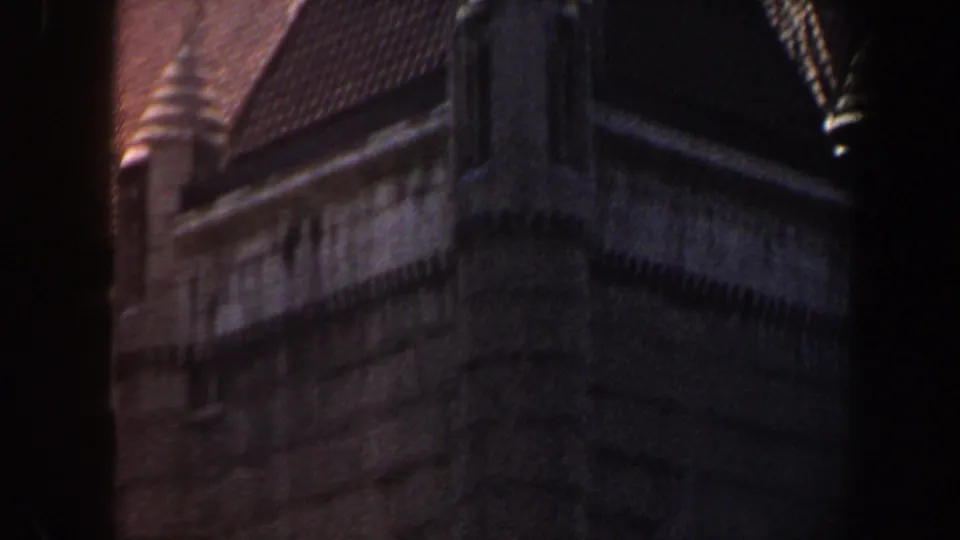 1964 Saint Louis home-movie frame showing a dark masonry building with arched windows, roof detail, and heavy shadow at the film edge.
