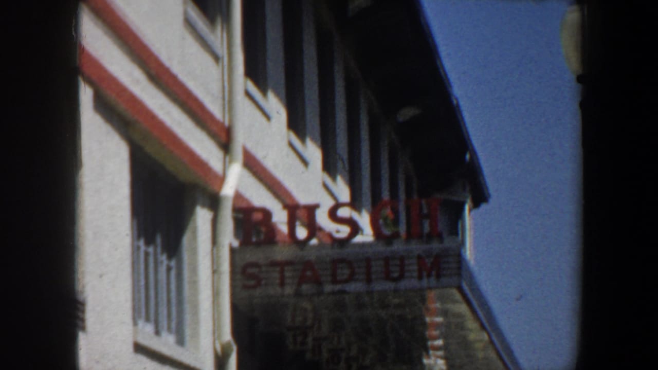 Busch Stadium lettering beside a white building exterior under blue sky.