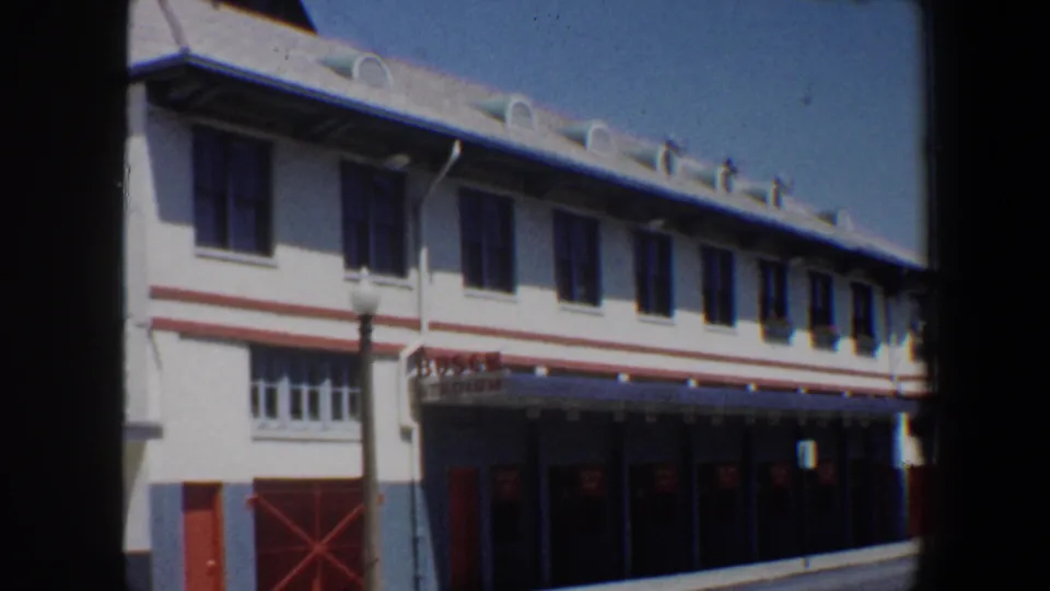 Saint Louis Busch Stadium exterior with red lettering above dark entrance doors, white facade, red trim, and blue sky.