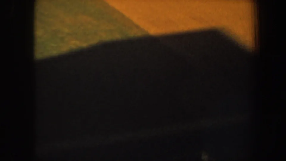The final 8mm frame is mostly obscured by dark shadow, with only a warm-toned upper strip and indistinct shapes visible.