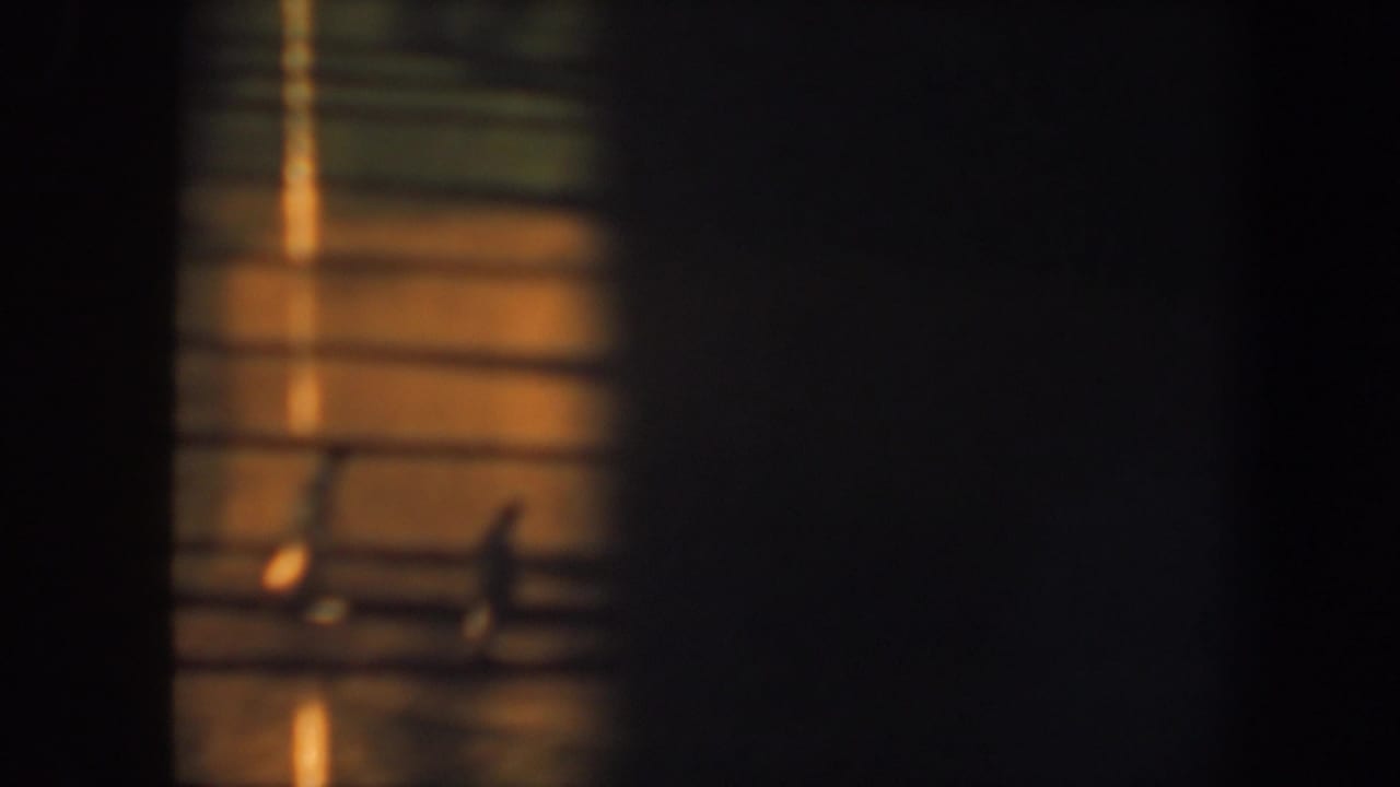 1964 Saint Louis 8mm frame showing a distant baseball player near field lines, with strong shadows and dark borders around the view.