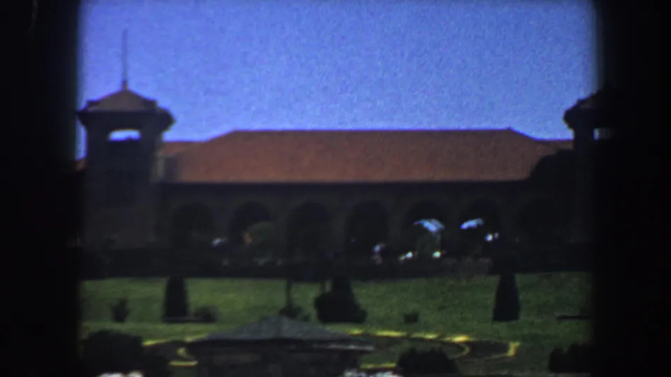 1964 Saint Louis 8mm frame holding on the church grounds, bell tower, red roof, and arched exterior facade.