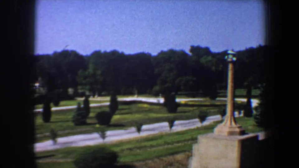 Saint Louis garden park footage from 1964 showing winding paths, clipped lawns, trees, shrubs, and a tall decorative pillar.