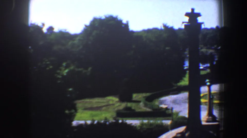 A 1964 Saint Louis estate garden view shows bright lawns, trees, and a curved driveway framed by dark architectural edges.