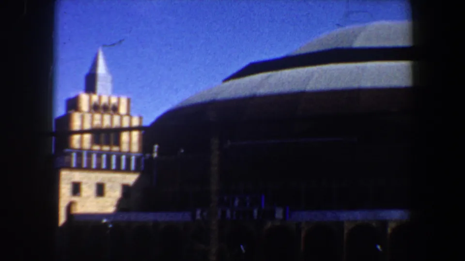 1964 St. Louis frame showing part of the sports arena building, adjacent tower, railing, and blue sky.