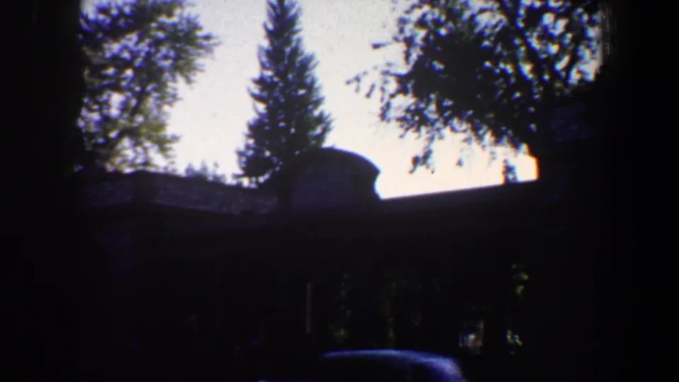 High-contrast 1964 St. Louis frame with a shaded building, trees, and a partial car shape near the bottom edge.