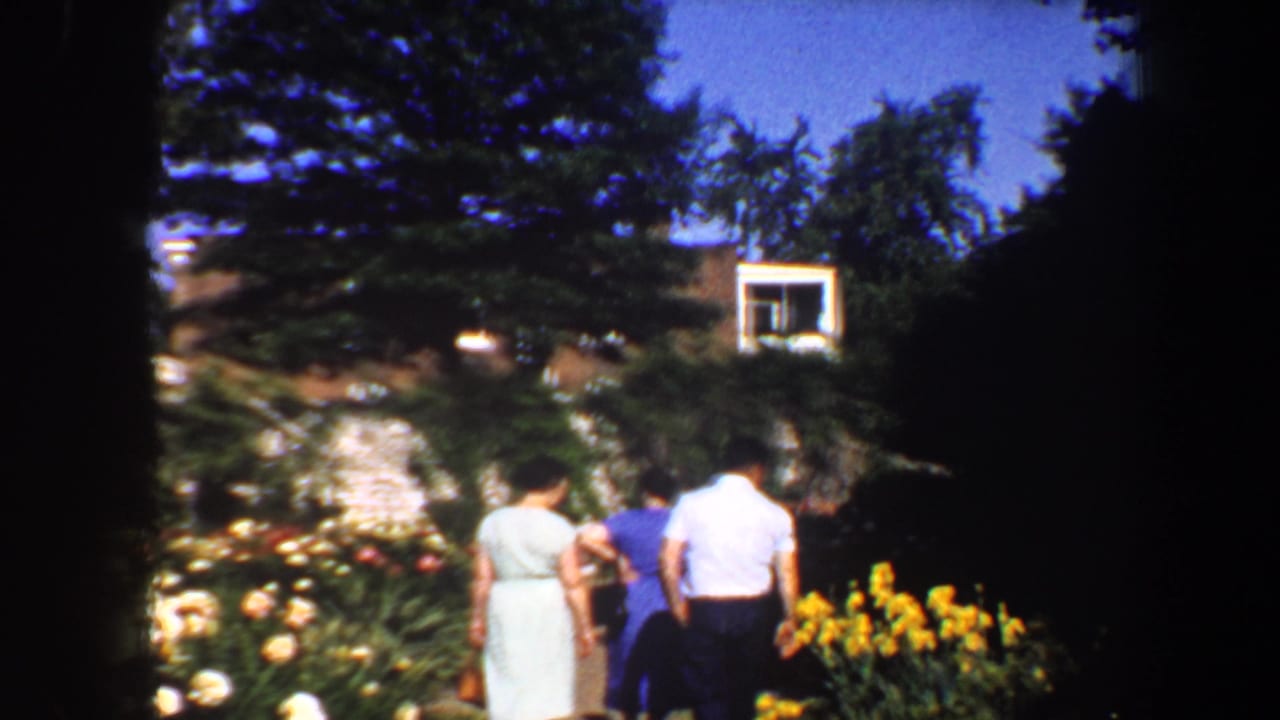 Three figures continue along a garden path with yellow flowers and trees around them.