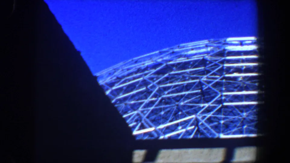 1964 Saint Louis frame with a geodesic-style metal dome seen through dark foreground shapes against a deep blue sky.