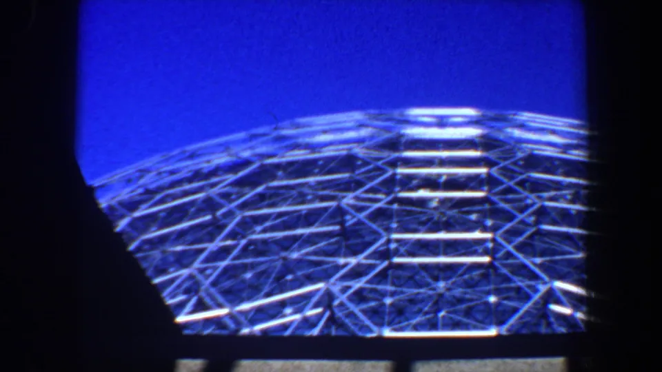 1964 Saint Louis footage shows a metal dome structure viewed through heavy dark framing, with blue sky above.