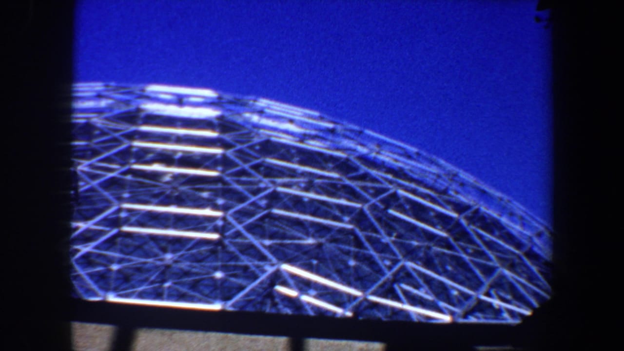 Geodesic glass dome and metal lattice under a blue sky.