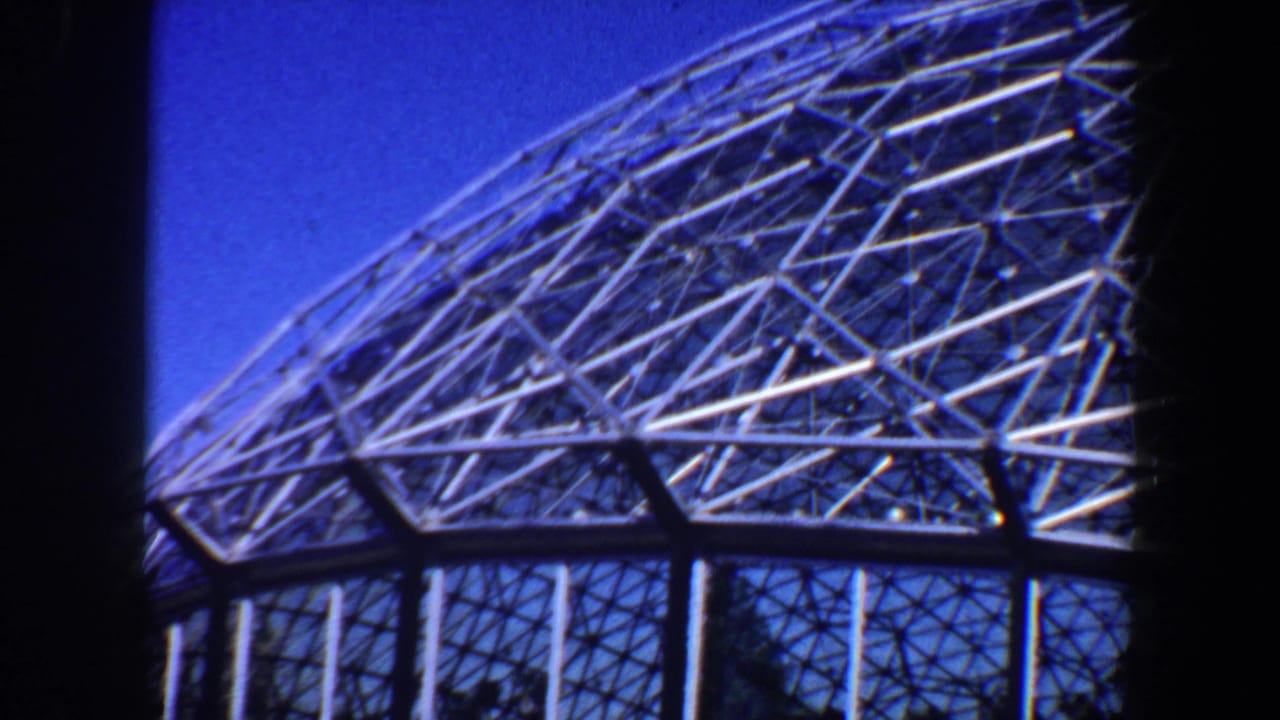 Low-angle view of a geodesic dome framework against a blue sky.
