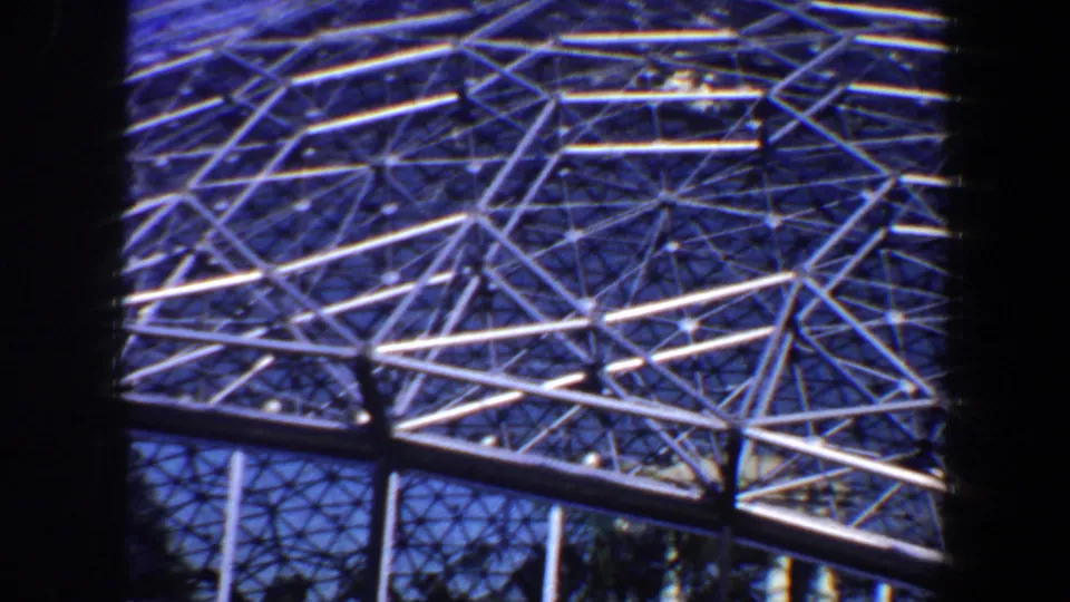 Close 8mm view of the geodesic steel pattern in Saint Louis, with lower supports and blue sky visible below the dome curve.