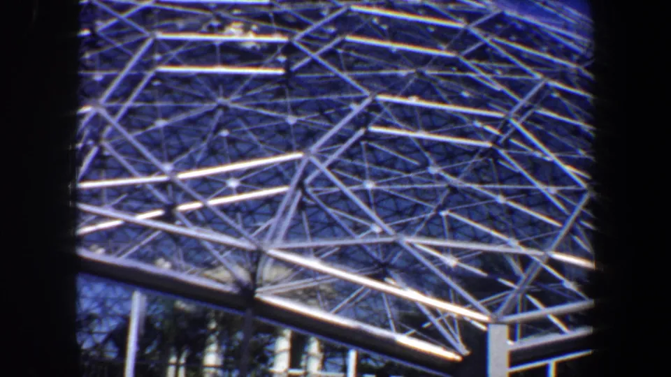 Final 1964 Saint Louis frame showing the dome's angular steel network, lower glazing, and dark foreground borders.