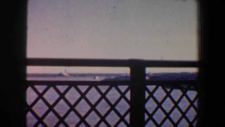 Saint Louis river scene from a bridge, with silhouetted railing, a central support, water, and distant shoreline visible through the frame.