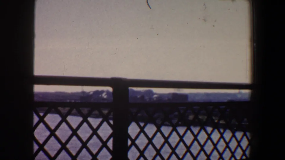 Final frame of the Saint Louis river view, with dark bridge latticework in front of the water and a distant tree-lined shore.
