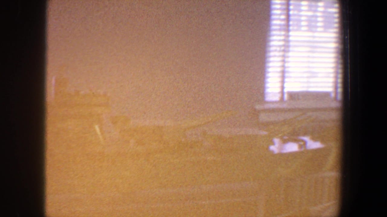 Overexposed amber room view with blinds and a faint ship model shape.
