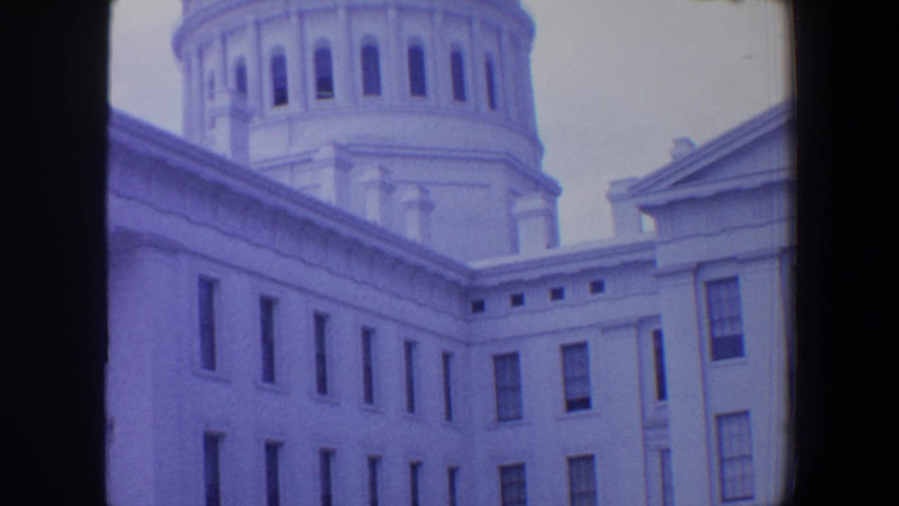 White classical building with tall windows and partial dome seen through 8mm contact-sheet framing.