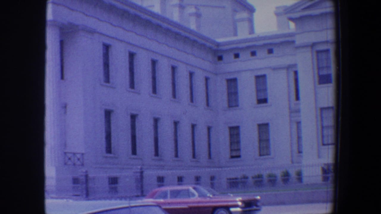 1964 Saint Louis street view of a white classical building facade with rows of windows and mid-century cars at the curb.