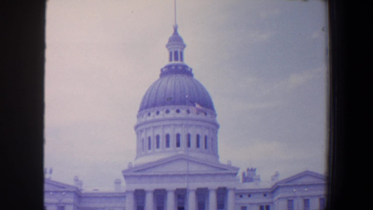 Gray dome and upper facade of a white neoclassical building.