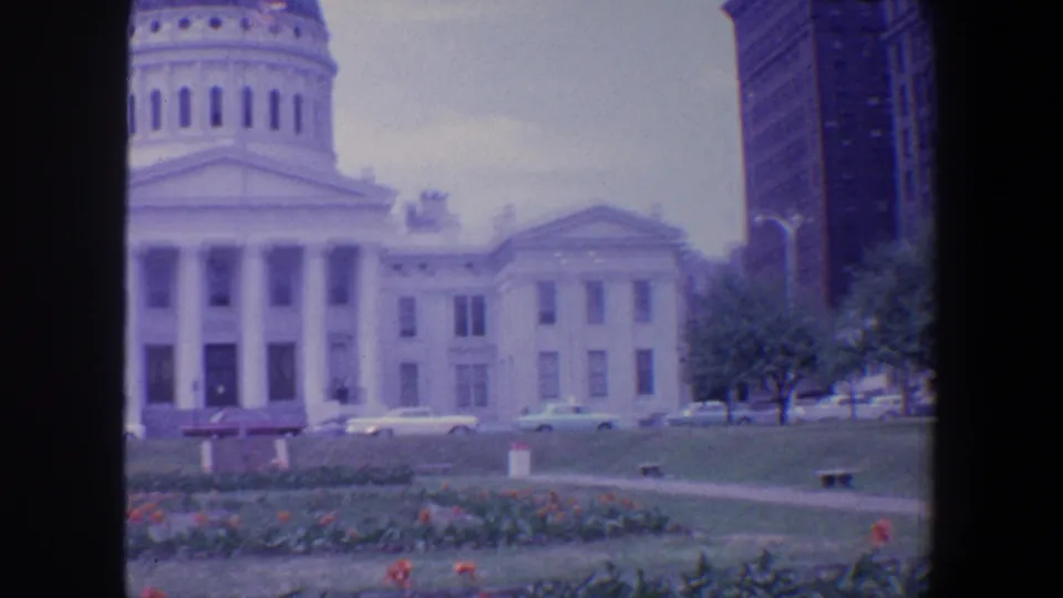 1964 Saint Louis footage shows the columned civic building partly framed with a taller downtown building and parked cars nearby.