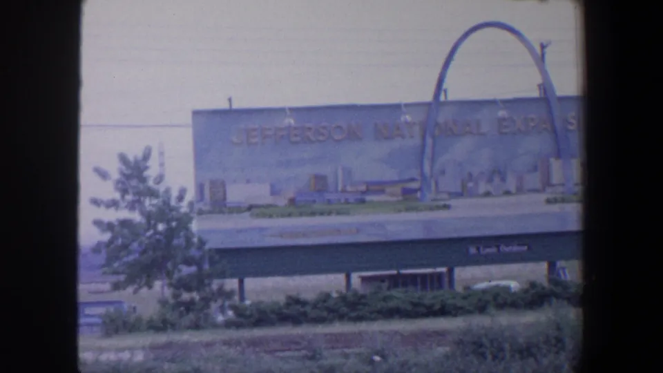 1964 Saint Louis 8mm frame showing the Jefferson National Expansion Memorial sign and the Gateway Arch in the background.