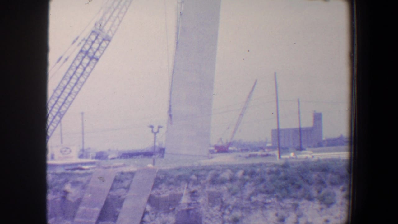 Crane and tall pale arch segment at an outdoor construction site.