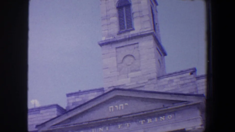 1964 Saint Louis frame showing a religious building facade with a stone tower, triangular pediment, Hebrew lettering, and partial Latin text.